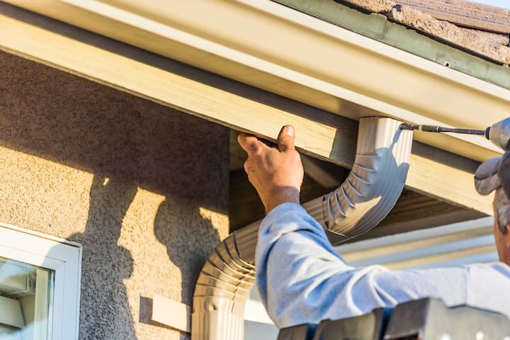 A team of workers installing seamless gutters on a commercial building in New Braunfels